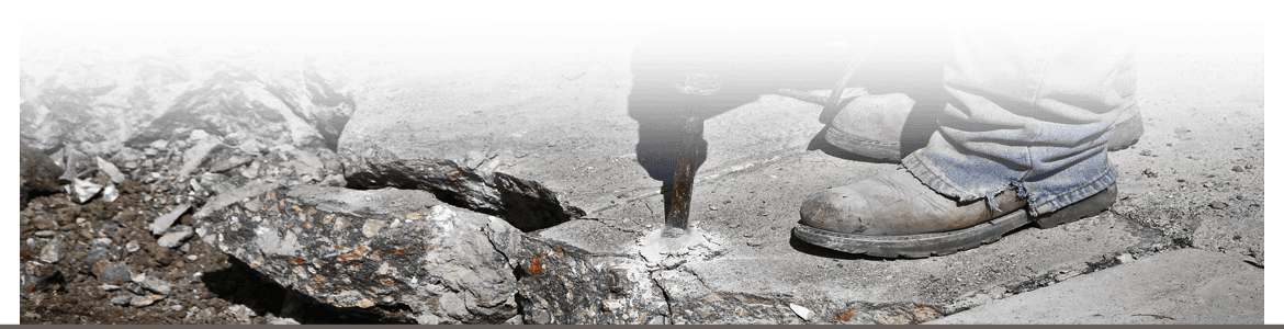 Worker using a jack hammer to break up and remove old concrete